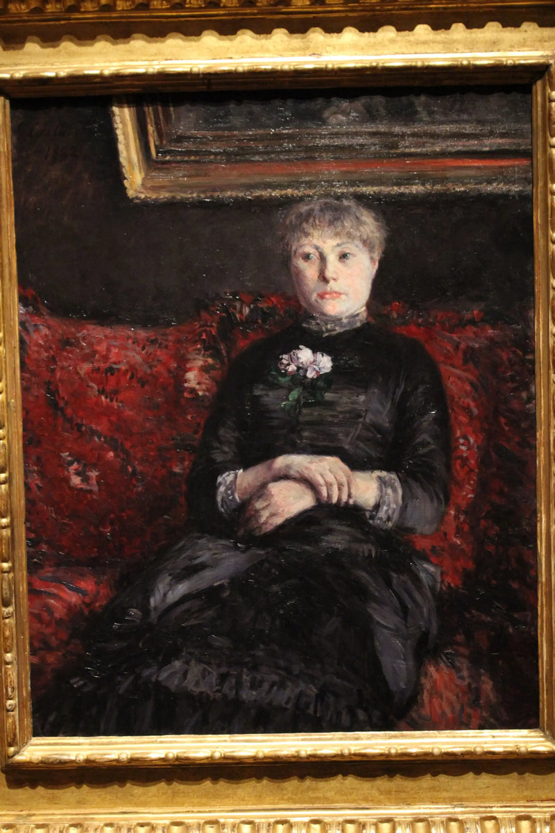 Kvinna som sitter på en soffa med röda blommor - Gustave Caillebotte